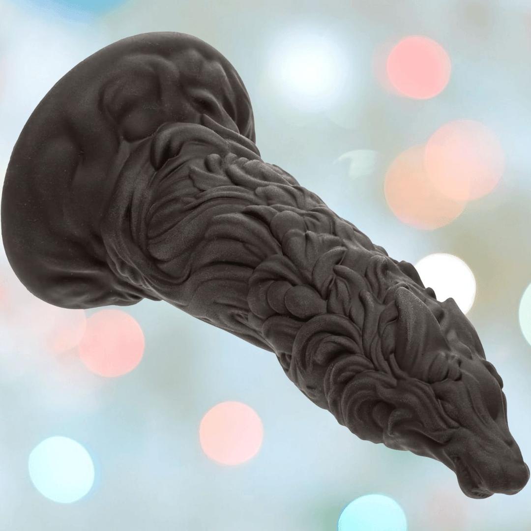 The CalExotics Monster Dong The Werewolf is a textured, dark silicone dildo with sculpted details and a suction cup base, inspired by werewolves, shown against soft pastel bokeh lights.