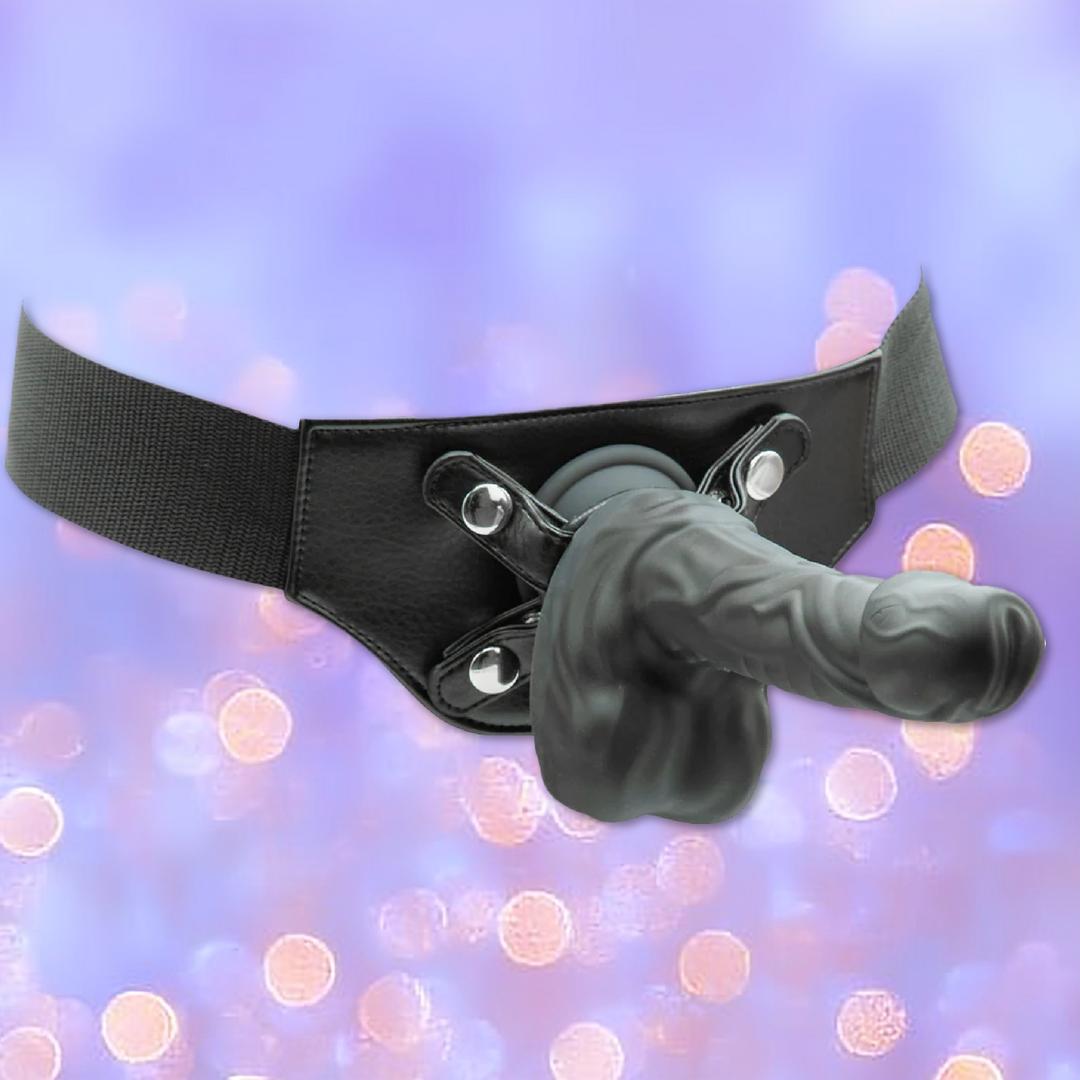 The BMS Naked Addiction Silicone Rotating & Thrusting Dildo - Noir 8.6" is a black strap-on harness with a lifelike silicone dildo, shown against a purple background with soft, blurred lights for an authentic look.