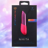 A product box for the Nu Sensuelle Nikita - Pink by NOVEL CREATIONS USA, featuring a visible pink and purple bullet vibrator, with branding and key features displayed on a blurred purple-blue background.