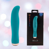 An emerald green Nu Sensuelle Velvet Touch Bella Vibrator with Turbo Boost by NOVEL CREATIONS USA stands upright beside its black box, showing the product image and name, all on a soft bokeh background. Made from body-safe silicone.