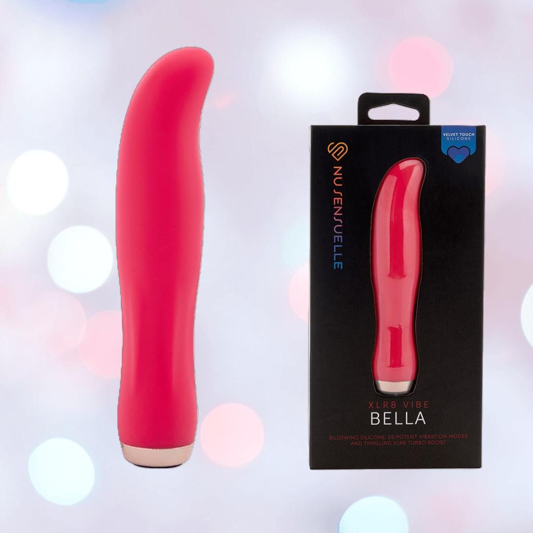 A hot pink, curved-tip Nu Sensuelle Velvet Touch Bella Vibrator with Turbo Boost by NOVEL CREATIONS USA stands upright next to its box, set against a soft pastel bokeh background.
