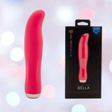 A hot pink, curved-tip Nu Sensuelle Velvet Touch Bella Vibrator with Turbo Boost by NOVEL CREATIONS USA stands upright next to its box, set against a soft pastel bokeh background.