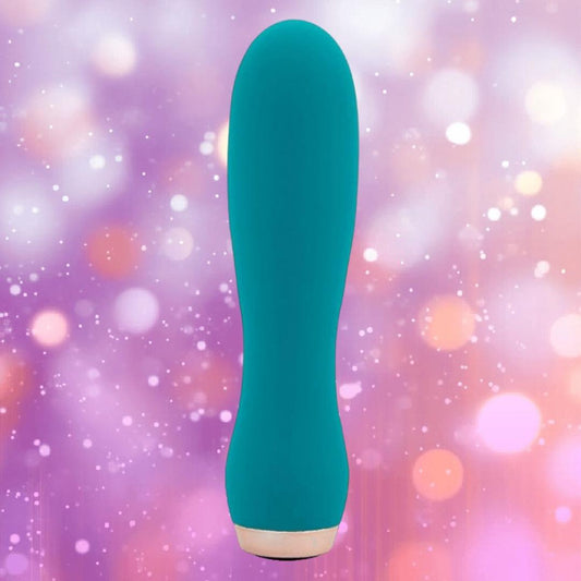 The Nu Sensuelle Velvet Touch Skye by NOVEL CREATIONS USA is an emerald green, cylindrical bullet vibrator with a rounded top and velvet touch silicone, shown standing upright against a soft, pastel bokeh background. 1080