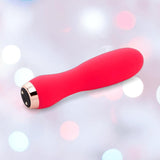 The Nu Sensuelle Velvet Touch Skye Vibrator with Turbo Boost by NOVEL CREATIONS USA in hot pink rests on a soft, pastel bokeh background, offering 20 vibration functions for customized pleasure.
