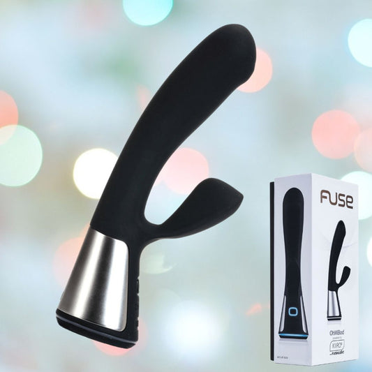 A black electronic device with a curved design from OhMiBod, the Fuse Interactive Dual Stimulator is Bluetooth-enabled for seamless connectivity. It is set against a blurred colorful bokeh background, with its box labeled "Fuse" featuring an image of the device displayed on the right side. 1080