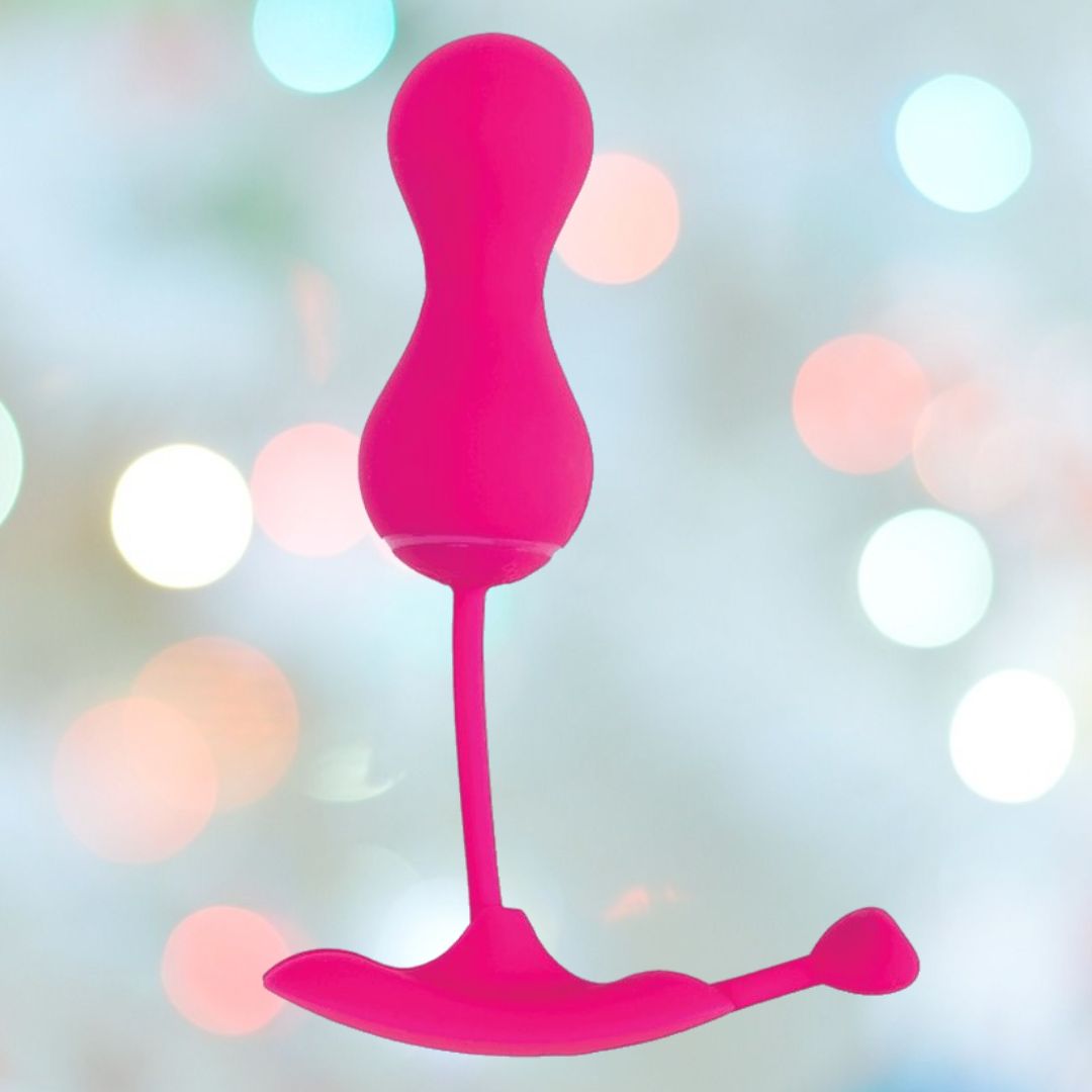The OhMiBod Lovelife Krush Smart Kegel Fitness in pink, by OhMiBod, features a bulbous top and flexible curved base, shown against pastel lights—a perfect device for pelvic floor fitness.