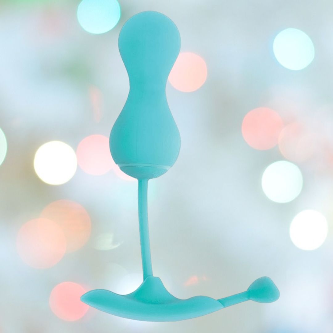 A turquoise OhMiBod Lovelife Krush Smart Kegel Fitness by OhMiBod, featuring a curved shape with a bulbous top and thin stem, is set against a softly blurred background with multicolored circular lights.