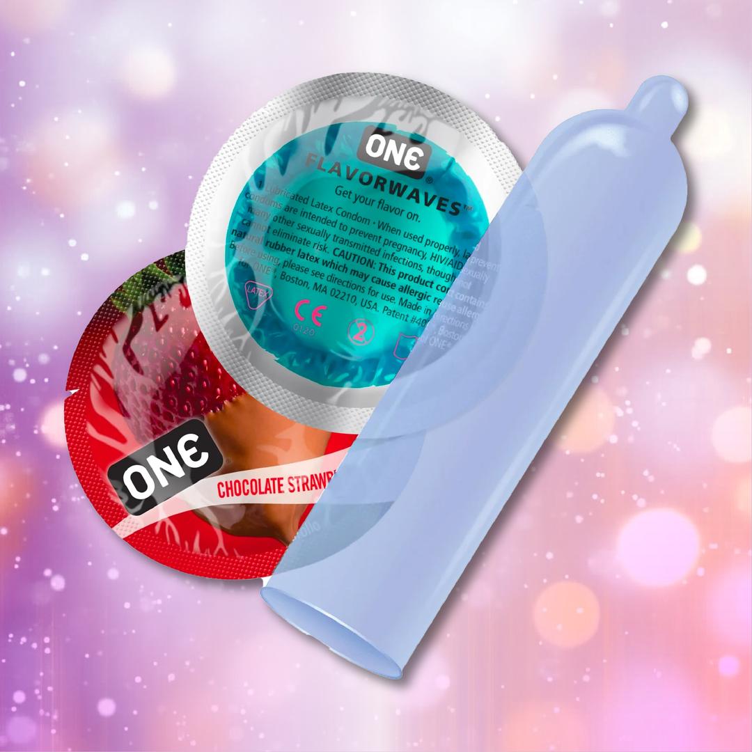 ONE Chocolate Strawberry Flavored Condoms 🍓 by ONE are shown: a red “Chocolate Strawberry” wrapper, a teal “Flavorwaves” wrapper, and an unrolled translucent condom, all set against a pink and purple bokeh background. Vegan-friendly.