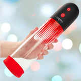 A hand holds the CalExotics Optimum Series Big Man’s Rechargeable EZ Pump, a transparent cylindrical device with red accents and a black buttoned top, against a softly blurred, multicolored background.