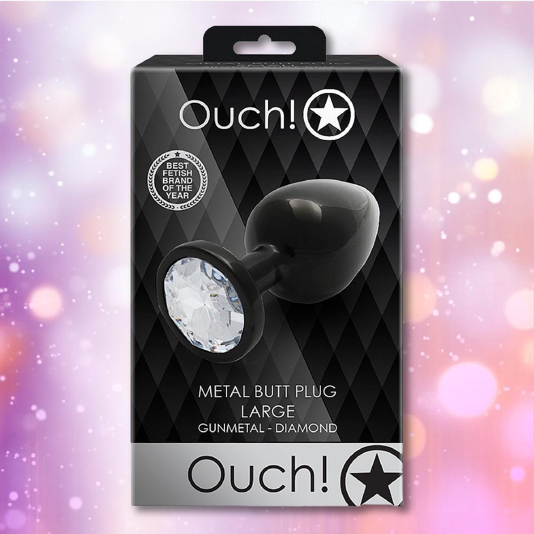 A black box labeled "Ouch!" by Shots displays the Ouch! Large Metal Butt Plug – Gunmetal with Diamond Base, featuring a geometric background and bold text: "Metal Butt Plug Large, Gunmetal – Diamond.