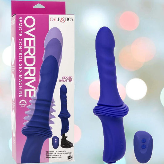 A blue Overdrive Portable Sex Machine Travel Thruster by CalExotics is displayed beside its packaging and a small remote, with blurred colorful lights in the background. 1080
