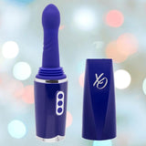 The CalExotics Overdrive Portable Sex Machine Travel Thruster is a purple massager with a rounded tip, detachable cap, and three buttons. It’s shown against a softly blurred pastel-colored background.