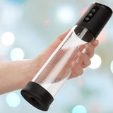 A hand holds the CalExotics Peak Rechargeable Penis Pump—a transparent, cylindrical device with a black lid and base, featuring three buttons on top for automatic suction. The softly blurred background adds light bokeh effects.