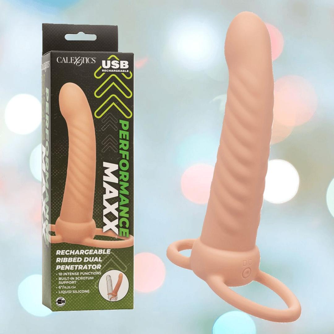 The Performance Maxx Rechargeable Ribbed Dual Penetrator - Ivory by CalExotics is shown beside its packaging, which features performance claims and USB recharge info. The toy offers ribbing and dual rings at the base for double penetration pleasure.