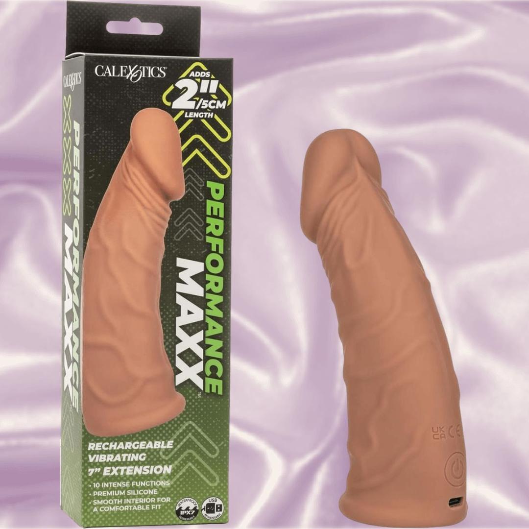The CalExotics Performance Maxx Rechargeable Vibrating Extension-Brown 7" stands beside its box, which touts a 2-inch length boost and multiple vibration functions for enhanced pleasure.