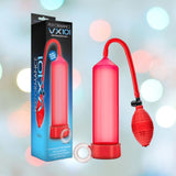 A red Performance VX101 Enhancement Pump, featuring a bulb, pressure gauge, and medical-grade ball pump, is placed next to its packaging. The box prominently displays the name "Performance VX101." In the background, blurred circular light patterns accentuate its sleek design by Blush Novelties for enhancement purposes. The product also includes a FREE Stay Hard Cock Ring.