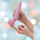 A person balances the BMS Pillow Talk Sultry Wand Massager in pink, featuring a quilted texture and rounded end, on their finger against a soft, pastel-lit background.