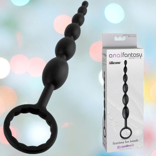 The Pipedream Anal Fantasy Collection First-Time Fun Beads, ideal for beginners in anal play, feature a black silicone design with a loop handle. The beads are showcased beside sleek packaging against a blurred colorful backdrop. 1080