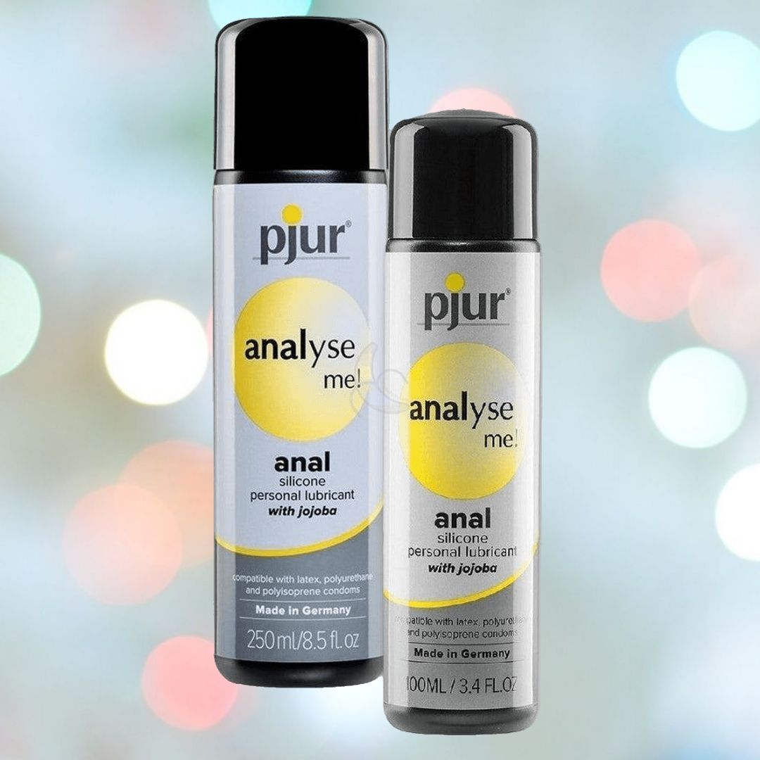 Two bottles, one black and one silver, of "Pjur Analyse Me! Silicone-Based Relaxing Anal Glide" by Pjur are showcased against a vibrant, blurred background with circular light spots. Discover the soothing anal glide offered by the 250 ml and 100 ml sizes of this luxurious silicone lubricant.