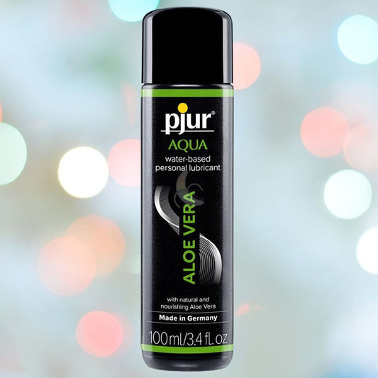 A bottle of Pjur Aqua Water-Based Lube with Aloe Vera (3.4oz) is pictured against a blurred background dotted with circular light spots. The label states that it is a water-based personal lubricant made in Germany and enriched with natural, nourishing Aloe Vera—ideal for enhancing your favorite sex toy experience. 1080