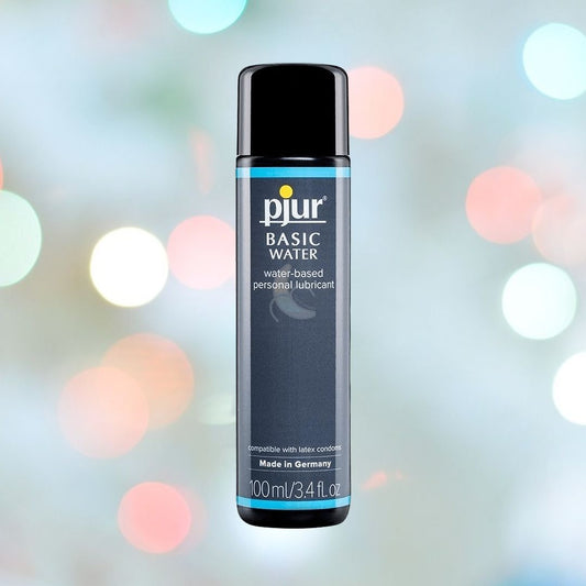 Bottle of Pjur "Basic" Water-Based Lubricant | 100ml (3.4oz), an affordable personal lubricant, set against a blurred colorful background. The blue and black bottle's label emphasizes its compatibility with latex condoms and gentle formulation for sensitive skin, proudly made in Germany. 1080