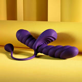 The Playboy Twisted Playground by Evolved Novelties, a purple silicone dual-ended toy with spiral textures and a round bead, rests on a yellow surface against a yellow background.