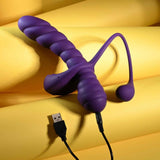 The Playboy Twisted Playground by Evolved Novelties, a purple ribbed silicone massager with a USB charging cable, is displayed on a yellow, soft-textured surface.