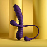 The Playboy Twisted Playground by Evolved Novelties, a purple silicone dual-ended toy with a ribbed, textured design, stands upright against a yellow background with cylindrical columns.