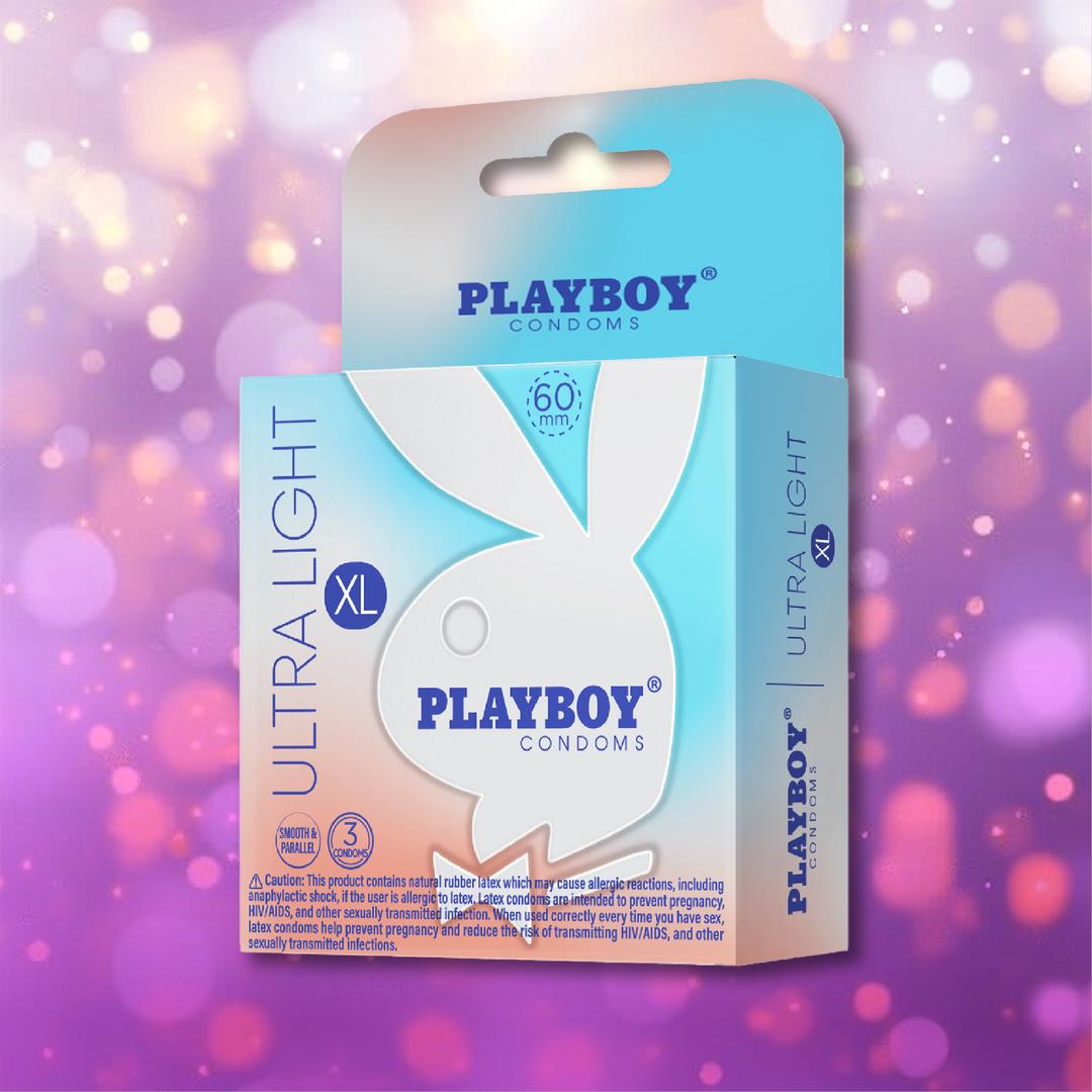 A box of Playboy Condoms - Ultra Light XL Extra Large in white and blue packaging with the Playboy bunny logo is shown against a pink and purple bokeh background, highlighting ultra-thin, extra-large condoms for maximum comfort.