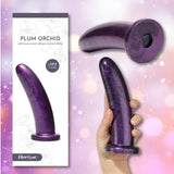 A hand holds the Fleshlight HerSpot Plum Orchid Dildo by Fleshlight beside its box, set against a dreamy pink and purple bokeh background.