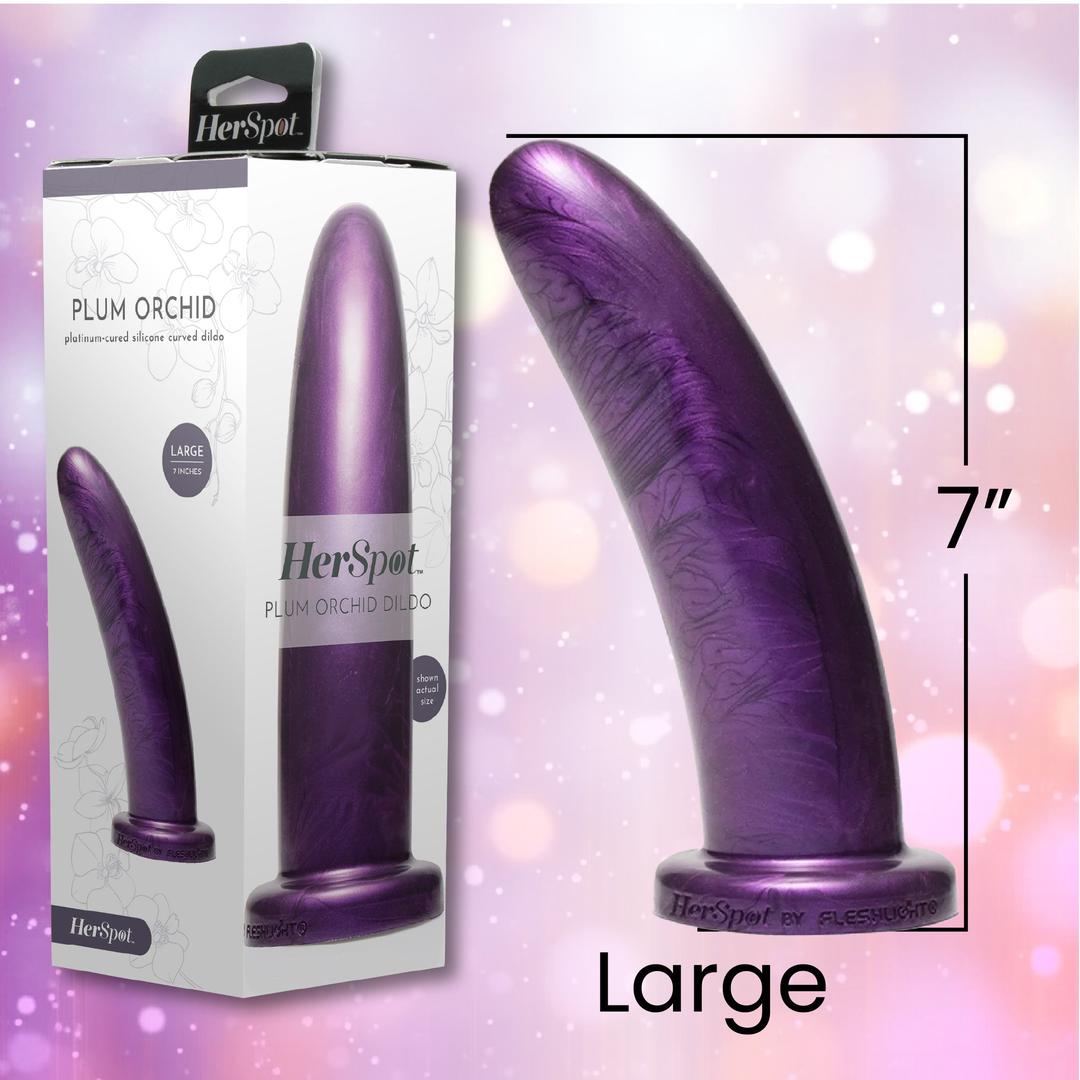 A purple, 7-inch luxury silicone dildo from Fleshlight stands upright next to its packaging, labeled "Fleshlight HerSpot Plum Orchid Dildo" with floral designs and the word "Large" visible on both the box and product.