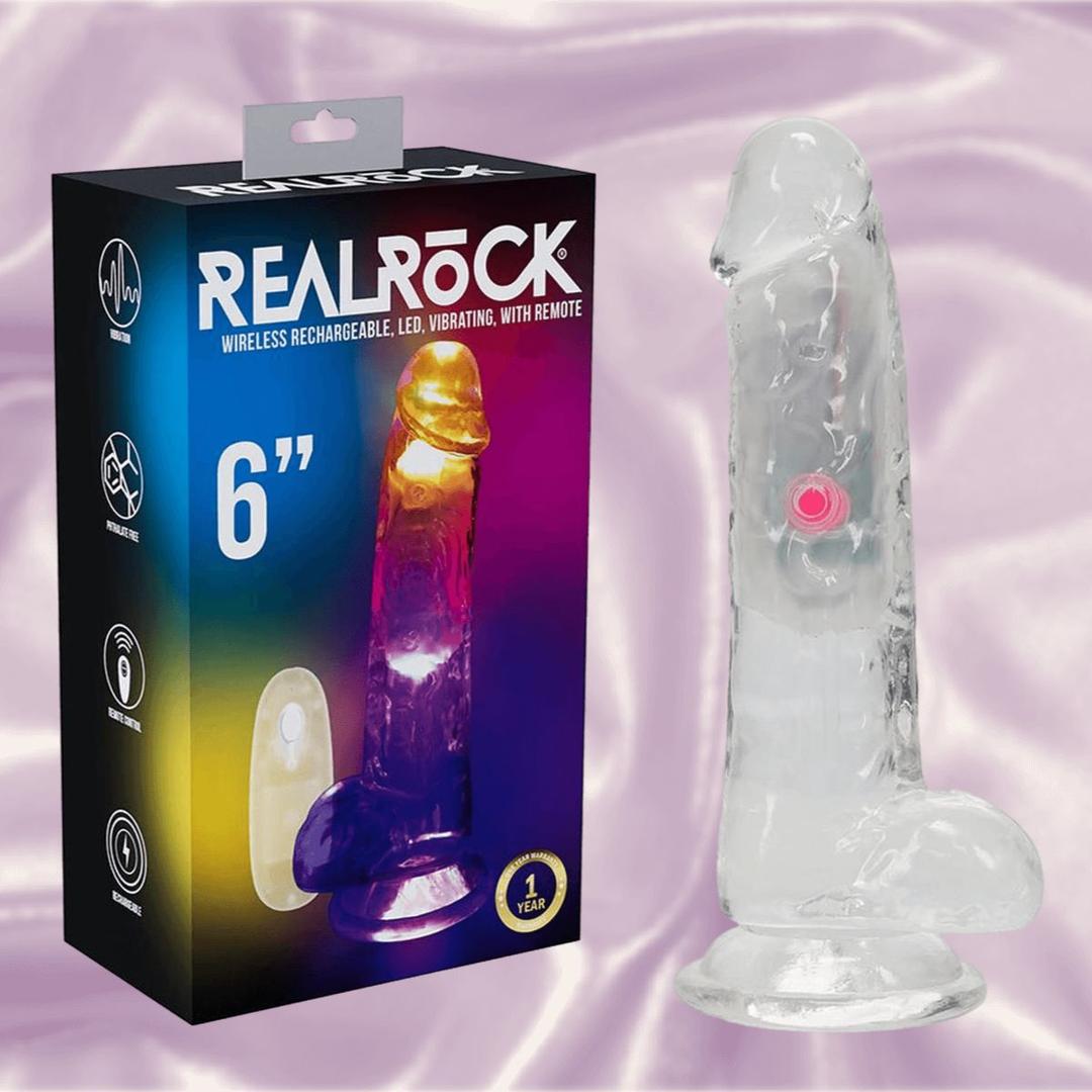 The RealRock Wireless Rechargeable LED Vibrating With Balls 6" by Shots America is a clear, realistic dildo with balls, a suction base, multiple vibration functions, remote control, and eye-catching LED light in colorful packaging.