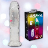 The RealRock Wireless Rechargeable LED Vibrating 6" dildo by Shots America is shown upright beside its black branded box, which features product details and vibrant imagery, all set against a softly blurred pastel background.