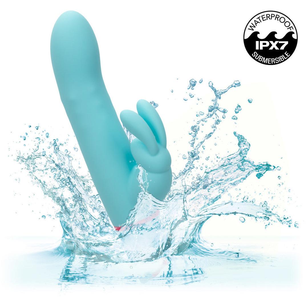 The CalExotics Love Bunny Beaded “G” Bunny, a blue dual-motor vibrator, splashes into water as an "IPX7 Waterproof Submersible" symbol appears in the top right corner.