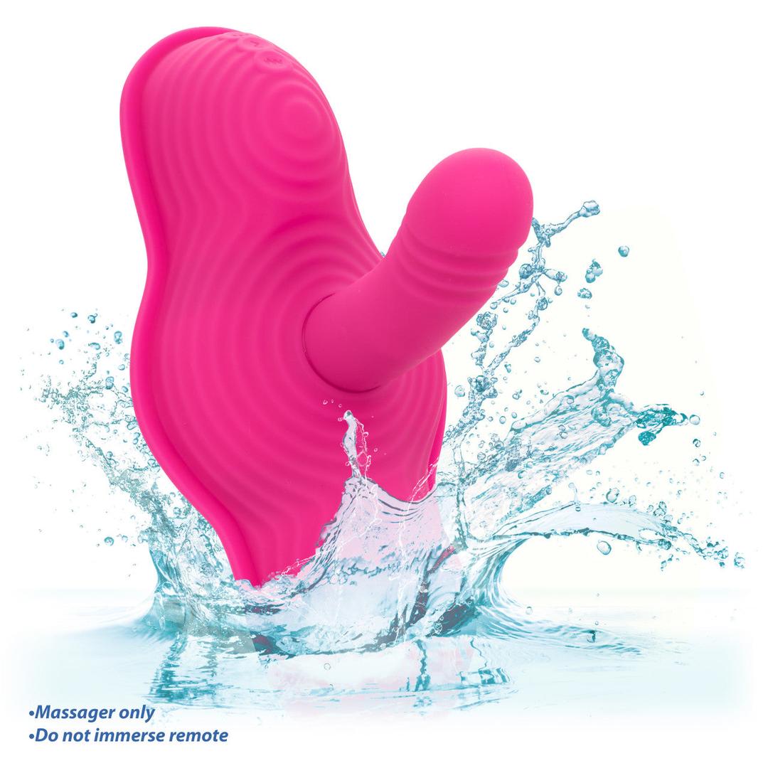 The Triple Rider Remote Control Ecstasy Rumbler by CalExotics, made of body-safe pink silicone, splashes in water with droplets and waves. Text says, "Massager only. Do not immerse remote." Background is white.