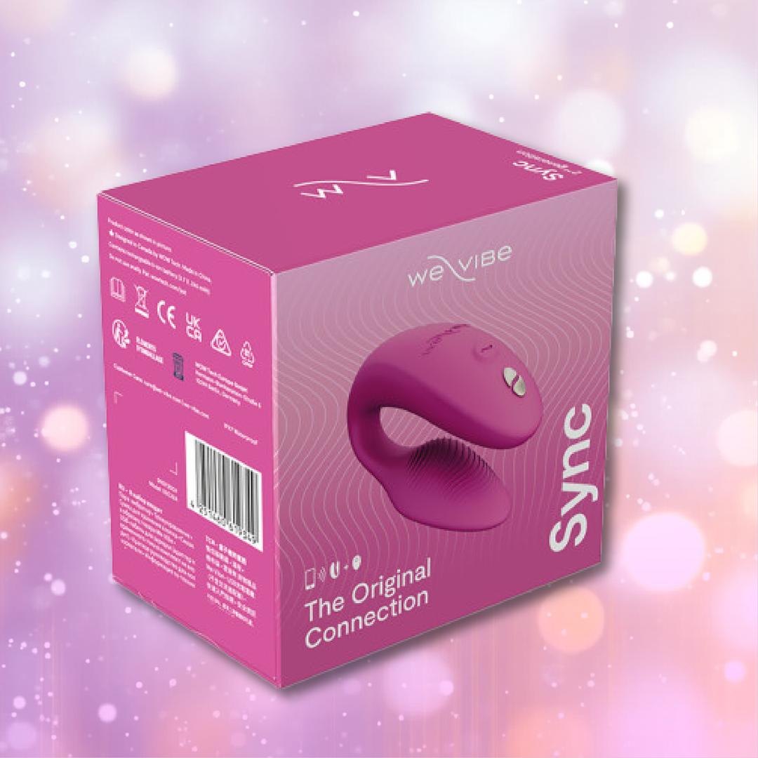 A We-Vibe Sync 2 Couples Vibrator with App - Rose product box featuring an image of the couples vibrator on the front, displayed against a softly blurred purple and pink background with gentle light bokeh effects.
