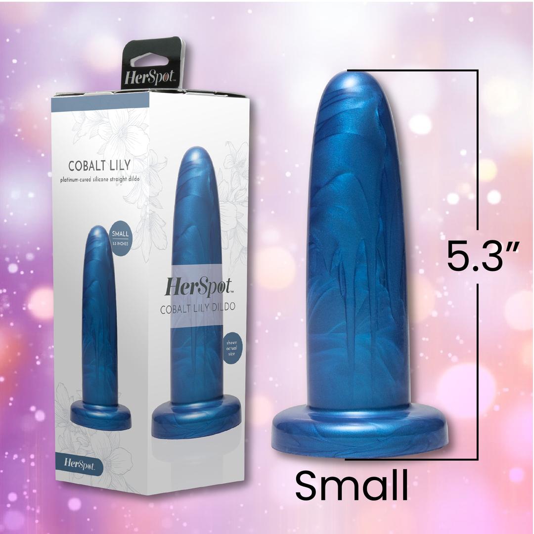 The Fleshlight HerSpot Cobalt Lily Dildo, a 5.3-inch blue toy by Fleshlight, stands beside its packaging featuring product imagery and branding, set against a pink and purple blurred background.