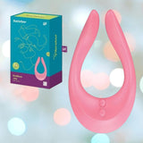 The Satisfyer Endless Joy Vibrator for Couples - Pink by Satisfyer is shown next to its teal and pink packaging, set against a soft, bokeh light background.