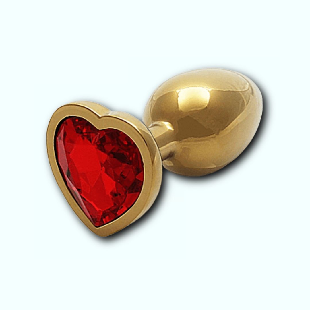 The Shots Ouch! Heart Gem Butt Plug Small - Gold/Ruby Red boasts a heart-shaped base adorned with a vibrant ruby red gem. This golden, metallic plug, featuring a sleek and shiny appearance as well as a tapered tip for easy insertion, stands out elegantly against the light blue background. Perfect for temperature play, this stunning accessory is both functional and visually captivating.