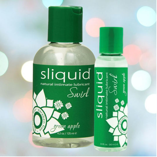 A pair of Sliquid Naturals Swirl Green Apple Flavored Lubricant bottles, one 4.2 oz and the other 2 oz, flaunting green labels accented with white text and a floral motif. This glycerin- and paraben-free lubricant is showcased against a backdrop of blurred, colorful lights. 1080