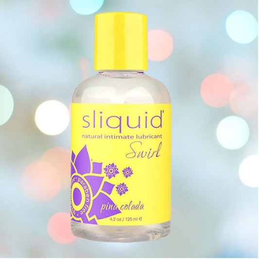 A bottle of Sliquid Naturals Swirl Pina Colada Flavored Lube, free of glycerin and parabens, features a yellow and purple floral label. This 4.2oz water-based lubricant is elegantly displayed against a soft bokeh effect in pastel colors, perfectly balancing design and functionality. 1080