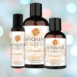 Three bottles of Sliquid's Organics Sensation Aloe-Based Warming Lube are displayed against a softly blurred background with multicolored lights. The labels emphasize its formula, which is free from glycerin and parabens, and made with 95% organic ingredients.