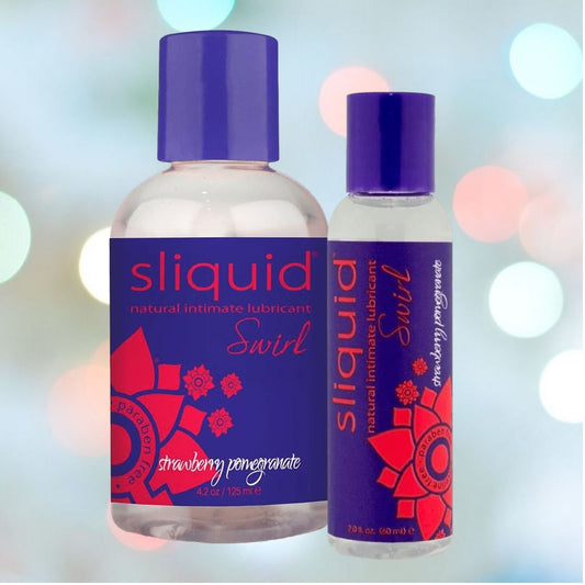 Two bottles of Sliquid Swirl Naturals "Strawberry Pomegranate" Flavored Lubricant 🍓 are displayed, with labels featuring purple and red floral designs. The setting is enhanced by a soft, bokeh light effect in the background. 1080