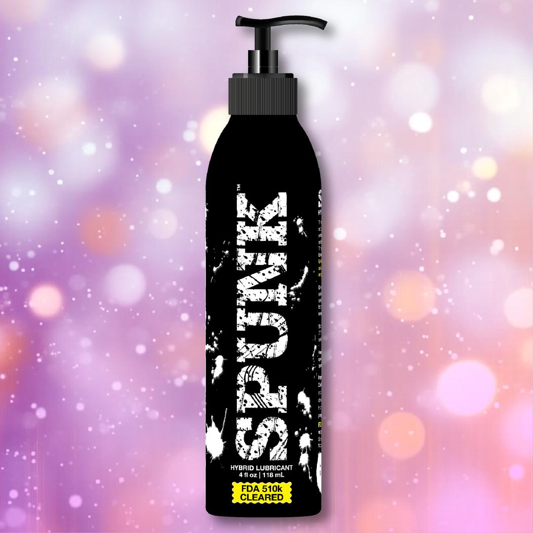 A black bottle of SPUNK Hybrid Lubricant by Spunk Lube with a pump dispenser is centered against a vibrant, blurred background featuring pink, purple, and white bokeh lights.