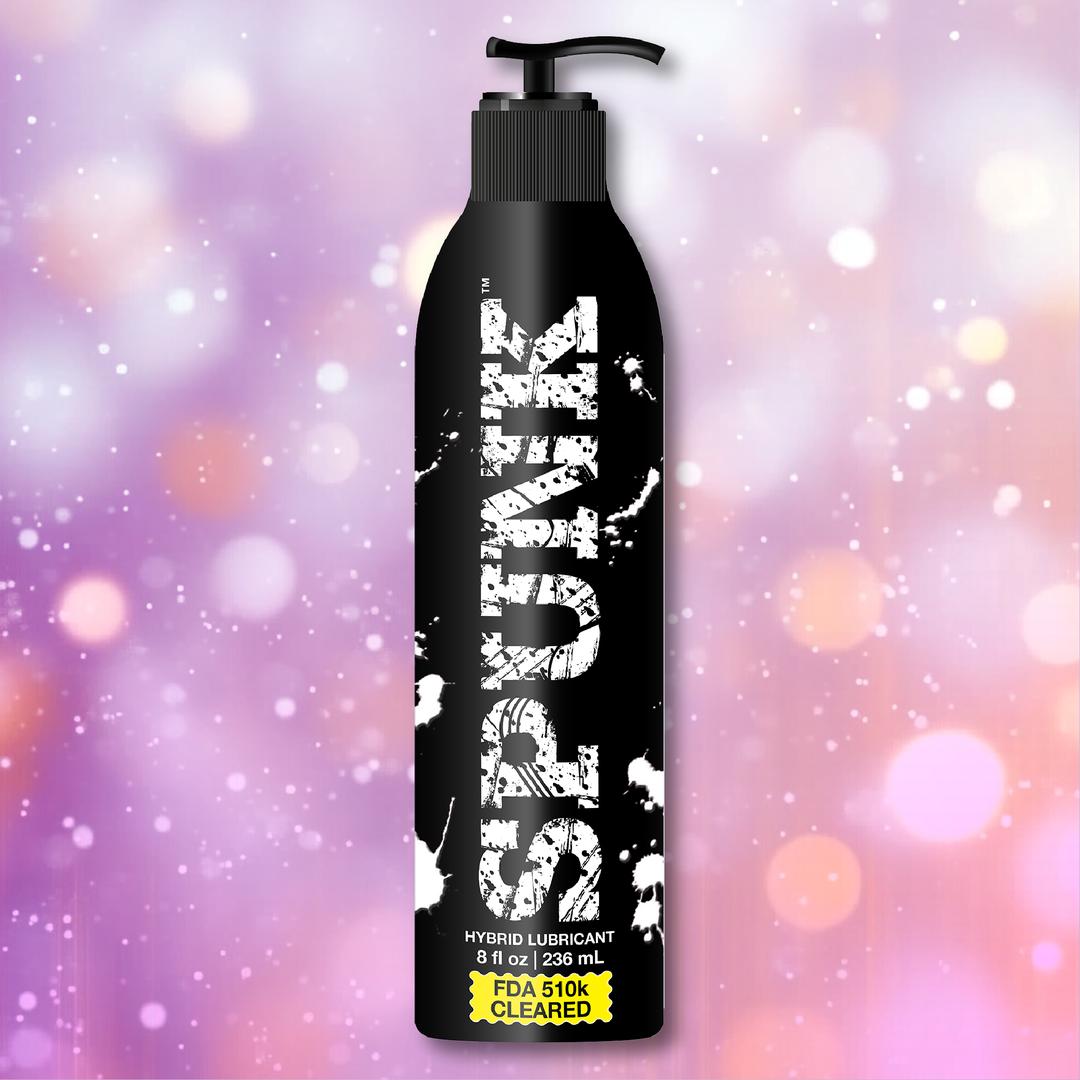 A black pump bottle labeled "SPUNK Hybrid Lubricant" by Spunk Lube stands against a purple and pink bokeh background.