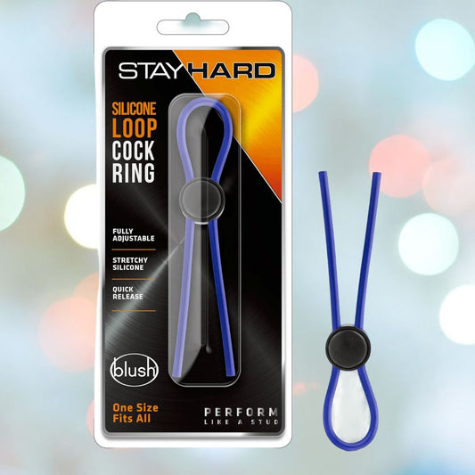 A packaged Stay Hard Silicone Loop Adjustable Blue Cock Ring with an adjustable black button. Text on the package reads: "Stay Hard," "Silicone Loop Cock Ring," "Fully Adjustable," "Stretchy Silicone," "Quick Release," and "One Size Fits All." Brand: Stay Hard by Blush. Background features a blurred bokeh light effect. 1080