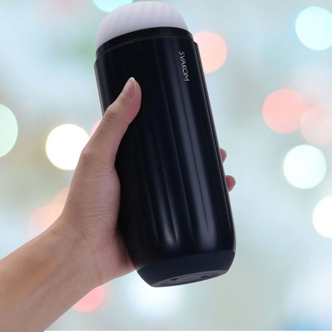 A hand holding a sleek, black cylindrical device known as the Svakom Sam Neo 2 Sucking and Vibrating Masturbator against a blurred, colorful background.