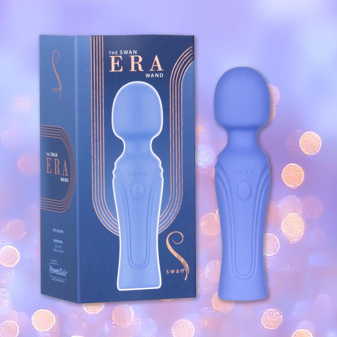 The Swan Era Wand by BMS, a blue personal massager with a powerful PowerBullet motor, stands next to its matching box displaying "The Swan ERA Wand" in gold lettering amid a purple background and glowing bokeh lights.