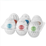 The TENGA Egg Variety Pack - Standard Penis Strokers (6 Pack) by Tenga features six white, egg-shaped sleeves, each with a colorful label and unique pattern, displayed in a clear tray.