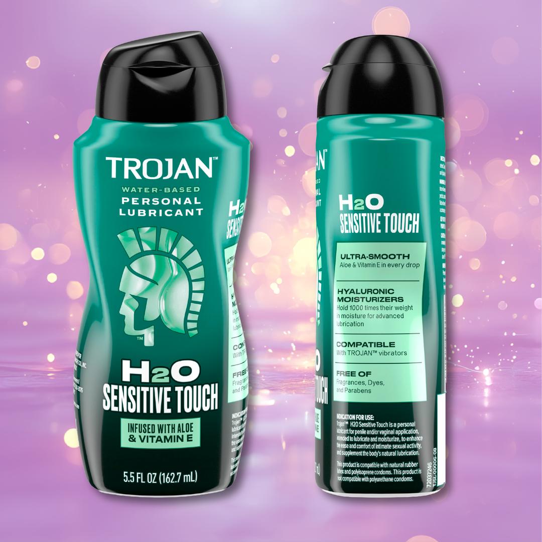 Two teal bottles of Trojan H2O Sensitive Touch with Aloe Lubricant (5.5oz) by Trojan, with visible product details and ingredients, displayed against a pink background accented with soft bokeh lighting effects.